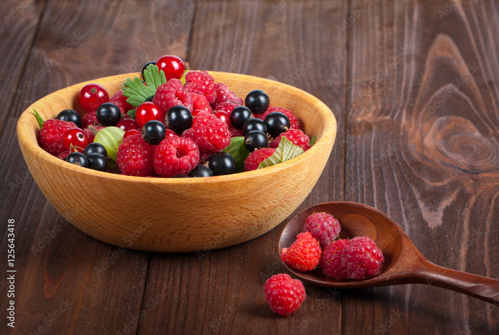 Fresh ripe berries in a wooden plate on the old wooden table. Useful natural food. Fruits and berries Fresh ripe berries in a wooden plate on the old wooden table. Useful natural food. Fruits and berries