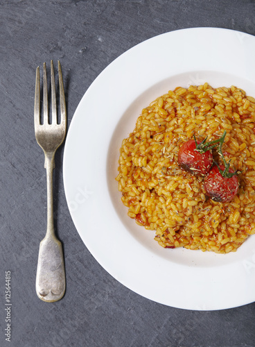 Aerial view of a dinner dish of tomato risotto on a rustic slate background