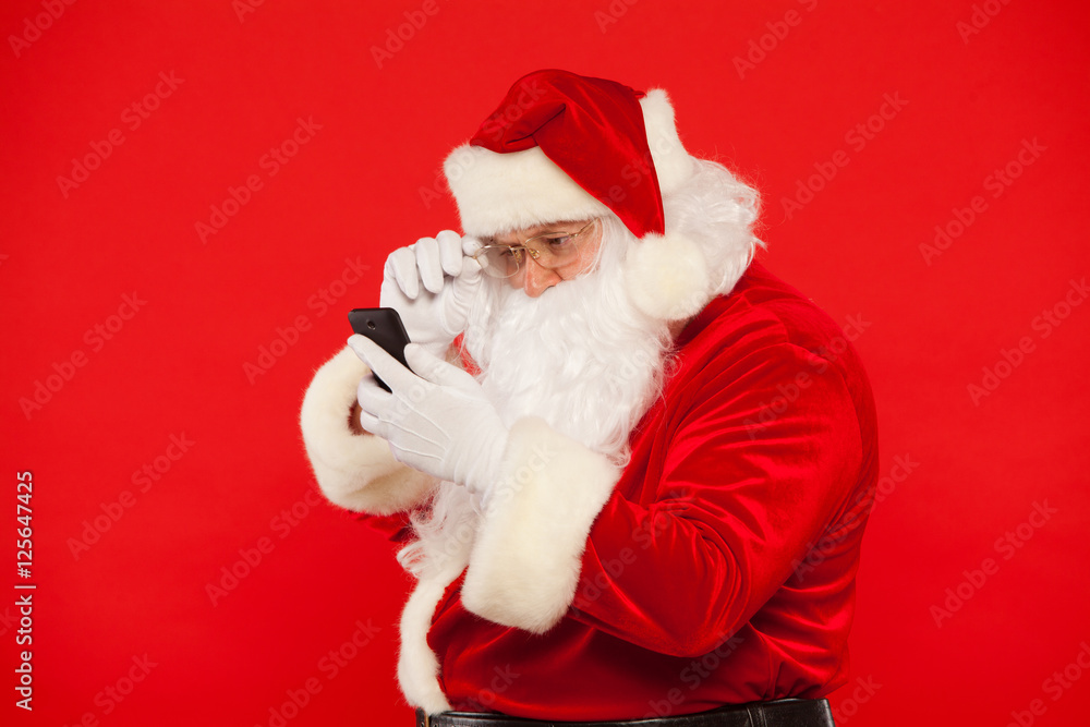 Photo of Santa Claus using mobile phone, on a red background. Christmas Photo of Santa Claus using mobile phone, on a red background. Christmas