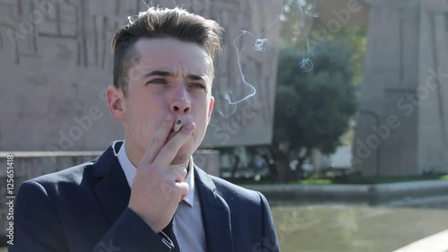 Young business man smoking cigarette in the street