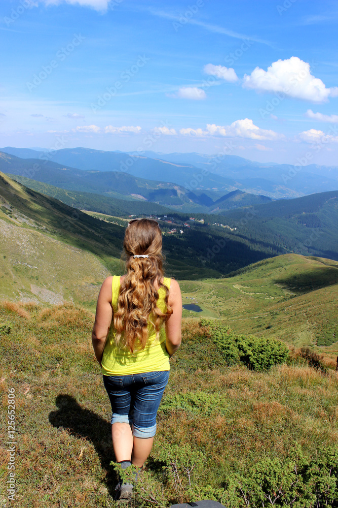 The girl tourist (young woman) with long hair looks at the mount The girl tourist (young woman) with long hair looks at the mount