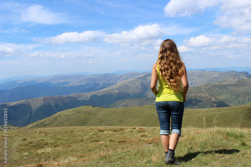 The girl tourist with long hair looks at the mountains in clear The girl tourist with long hair looks at the mountains in clear