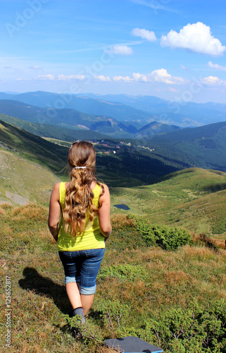 The girl tourist (young woman) with long hair looks at the mount