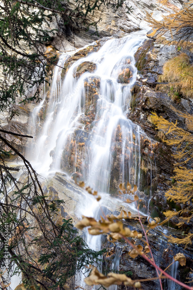 Obraz premium waterfall in the mountains and the autumnal trees, long exposure