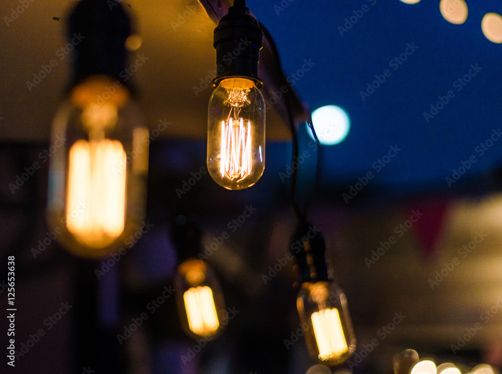 Vintage antique hanging light bulbs at a street food market. Holidays and business good idea concept.