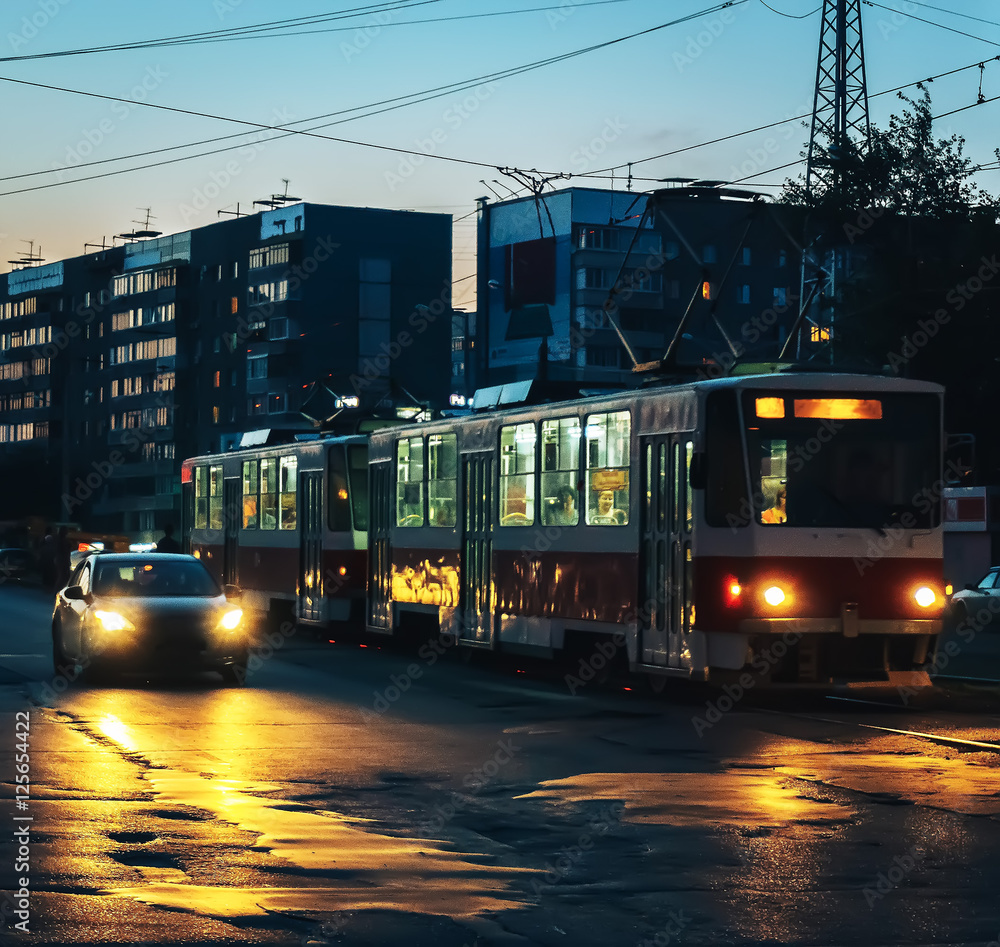 Obraz premium tram, car, dusk, city, people, headlights, dark house in the background