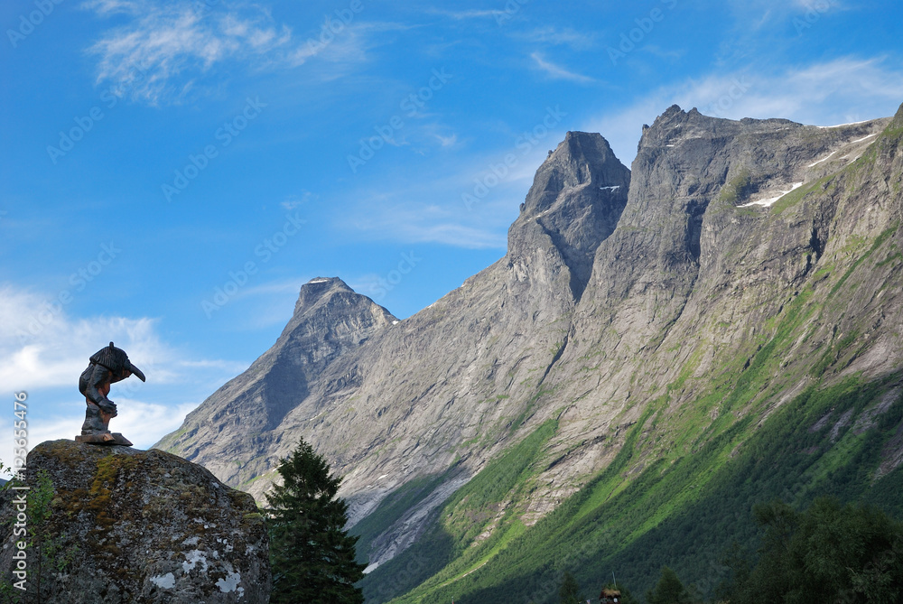 Wooden troll and mountain crest against the blue sky. Trollstigen.