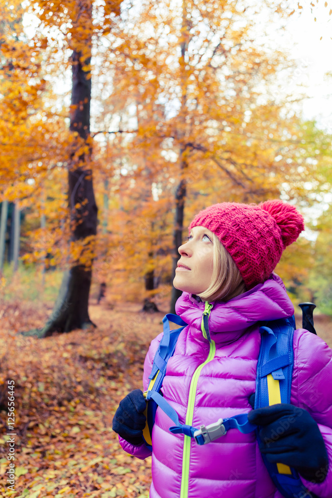 Hiking woman with backpack looking up at inspiring autumn trees Hiking woman with backpack looking up at inspiring autumn trees