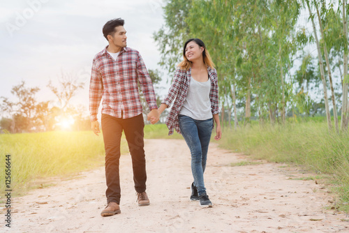 Young couple in love walking on rural road holding hands talking