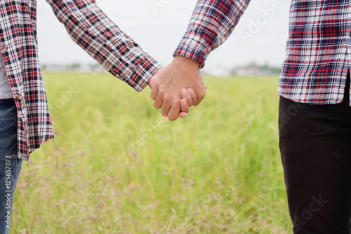 Close Up of loving couple holding hands while walking meadow fie