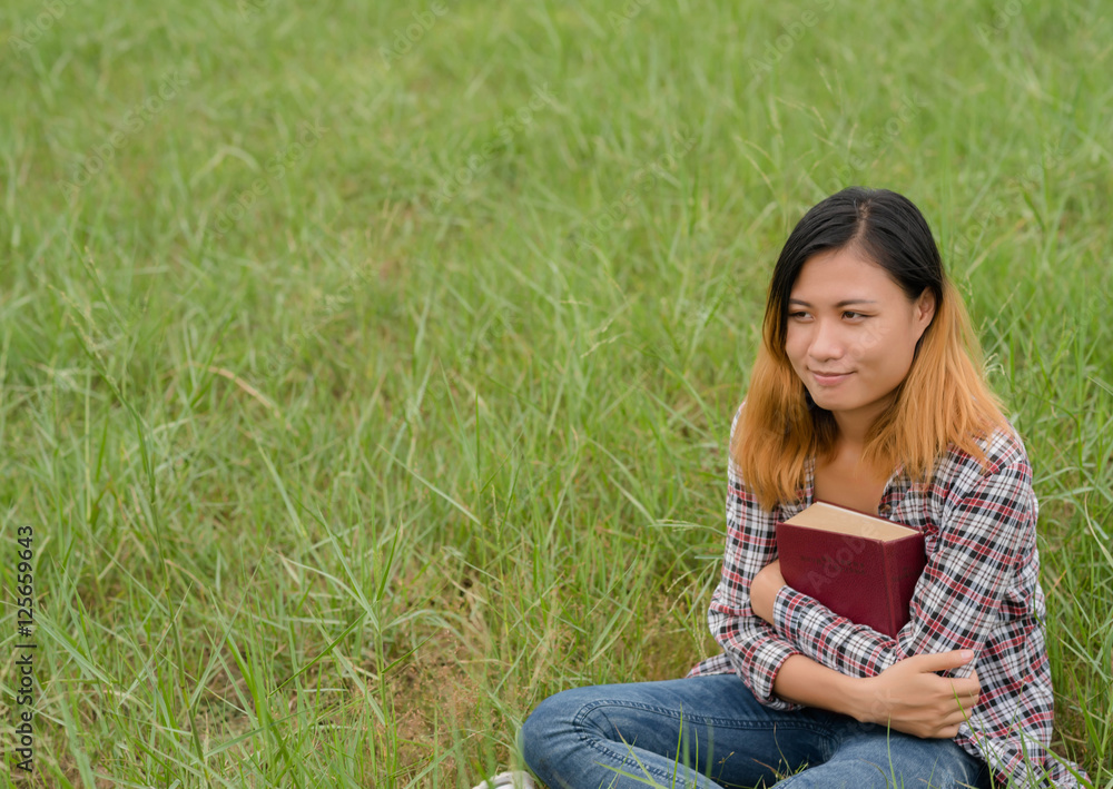 Young woman reading book on meadows field. Young woman reading book on meadows field.