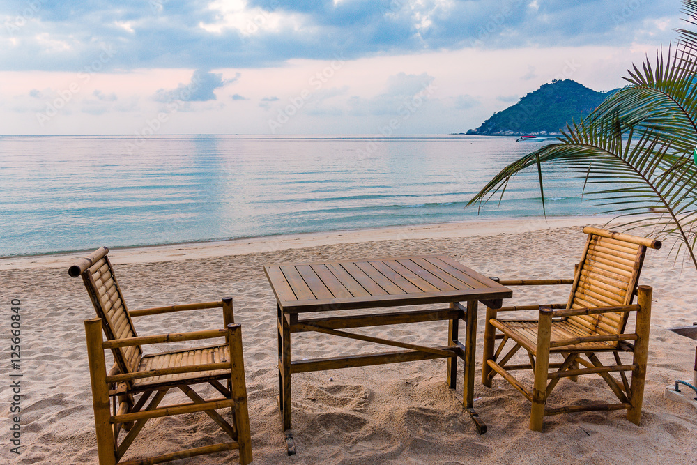 Table and chairs in the sunrise at a tanquil beach in Thailand