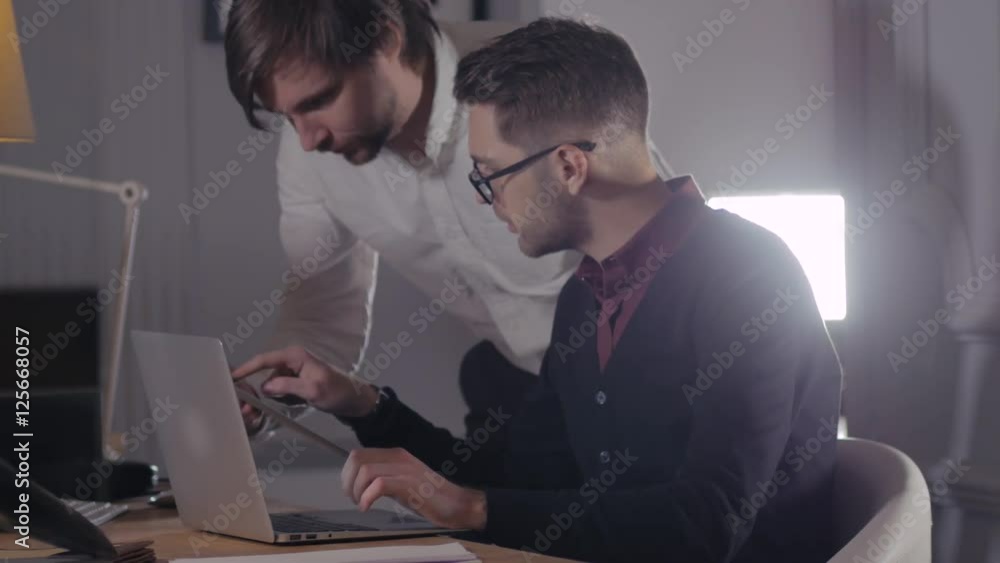 two young businessmen discussing data in touchpad at meeting. Group of handsome freelancers in modern office with devices laptop and tablet. Creative people. two young businessmen discussing data in touchpad at meeting. Group of handsome freelancers in modern office with devices laptop and tablet. Creative people.
