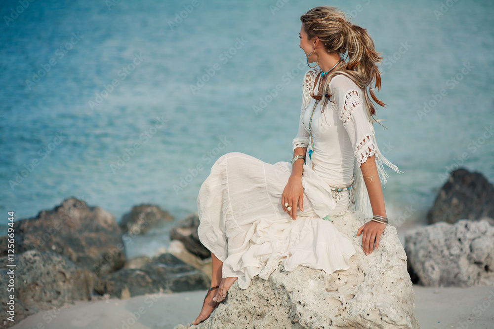 Naklejka premium beautiful boho woman on stone at sea shore