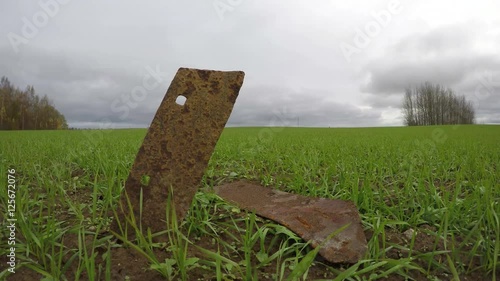 Two rusty young old tractor plow iron details in wheat field on windy overcast day, time lapse 4K photo