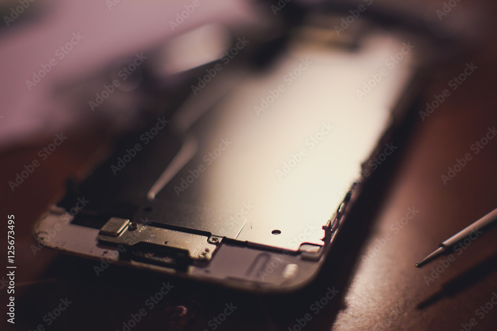 A close-up process of disassemble and dismantle modern mobile phone smartphone with broken shattered display glass and changing details at home A close-up process of disassemble and dismantle modern mobile phone smartphone with broken shattered display glass and changing details at home