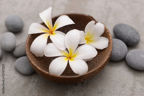 Beautiful Composition of frangipani in wooden bowl with spa stones