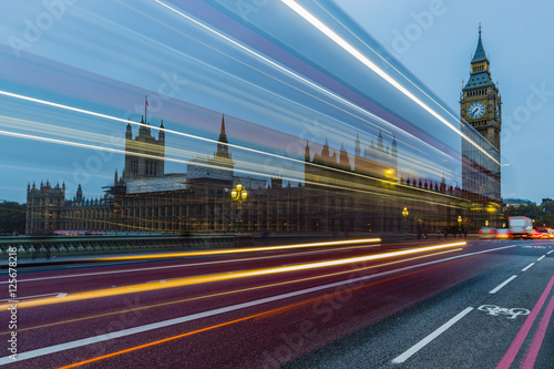 London, England, UK. Red buses blured in motion on Westminster bridge with Big Ben, the Palace of Westminster in early morning before sunrise.