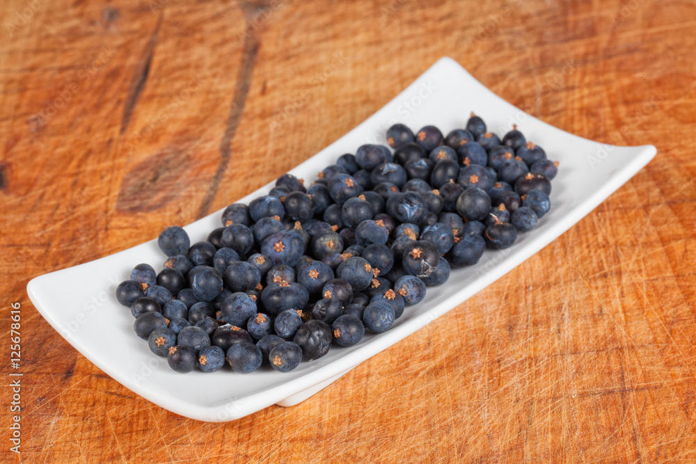 Frisch geerntete Wacholderbeeren in weißer Schale auf altem Holz Frisch geerntete Wacholderbeeren in weißer Schale auf altem Holz