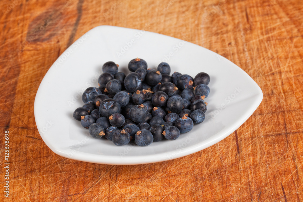 Frisch geerntete Wacholderbeeren in weißer Schale auf altem Holz Frisch geerntete Wacholderbeeren in weißer Schale auf altem Holz