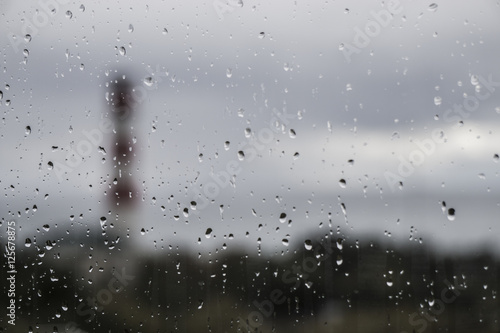 Lighthouse on the sea for wet glass with raindrops
