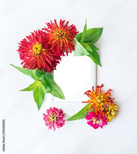 Electronic book, surrounded by flowers zinnias photo