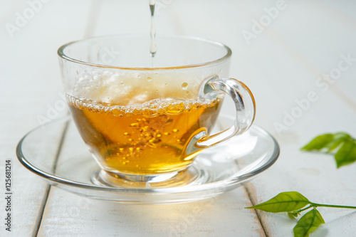 Warm cup of tea and leaves tea on white wooden
