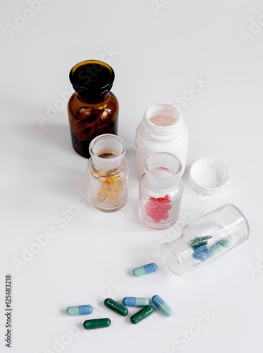 colored pills in glass bottles on white background
