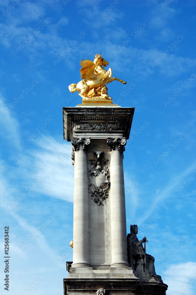 Fototapeta premium Gilded Pegasus sculpture on the column of Alexandre III bridge over the river Seine in Paris, France. The bridge was built in 1896