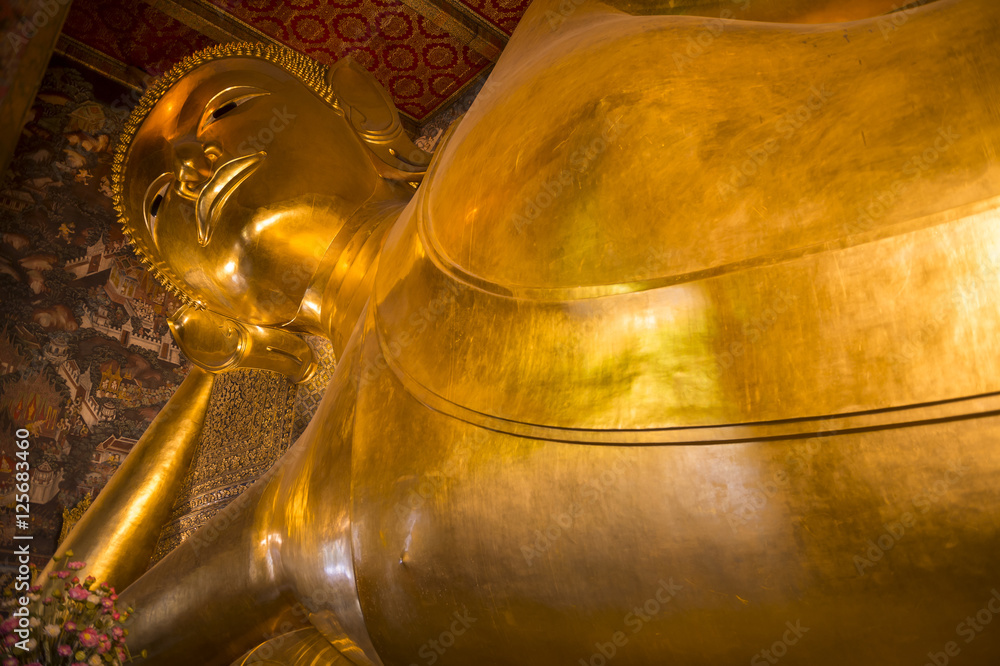 Temple of the Reclining Buddha in Bangkok Thailand close-up of the giant golden statue head and shoulders