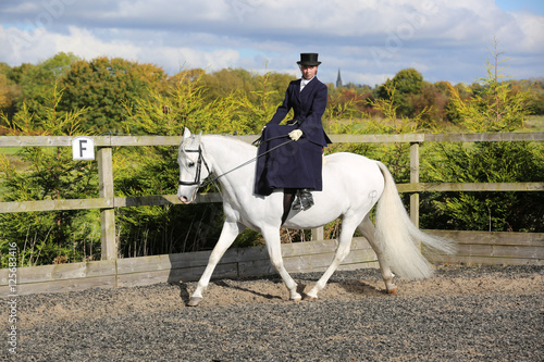 Girl riding white horse side saddle