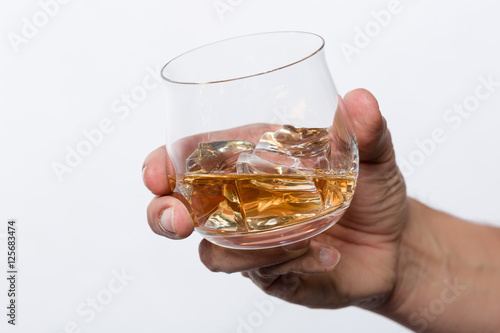 Hand hält Whiskeyglas mit Whiskey auf Eis