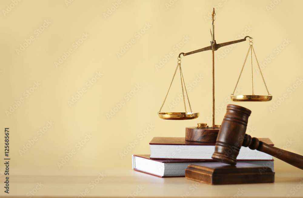 Justice scales, judge's gavel and books on wooden table and beige background Justice scales, judge's gavel and books on wooden table and beige background