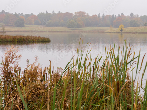 Early morning Autumn mist over lake at Tatton Park, Knutsford, Cheshire, UK