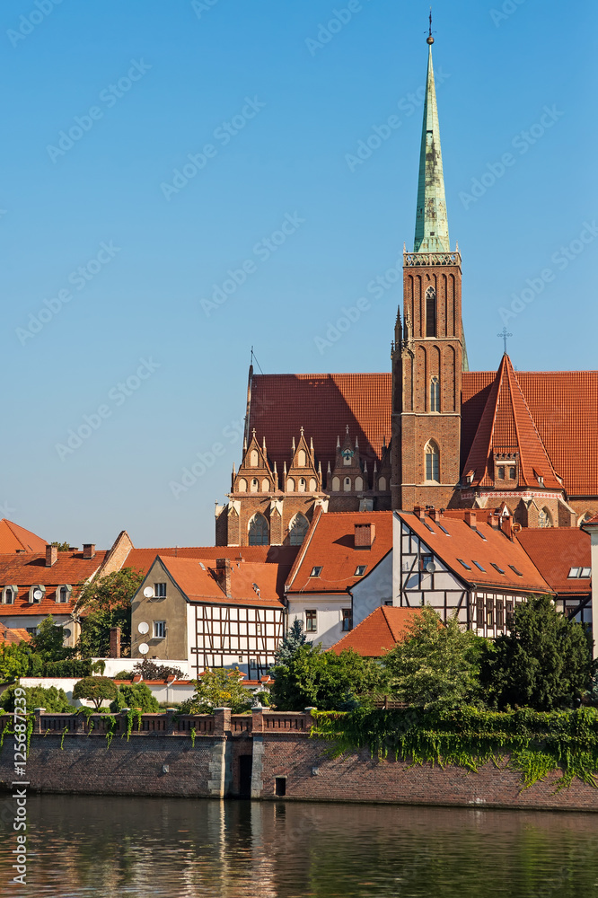 Fototapeta premium Wroclaw city, view from embankment on odra river and tumski island and catholic Church of the Holy Cross and St. Bartholomew. Famous touristic polish postcard view