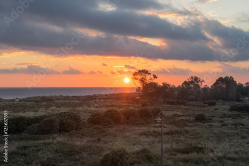 Dawn with bright Sun over Mediterranean Sea with vintage street lamp in foreground. Nei Pori village, Pieria, Greece. 