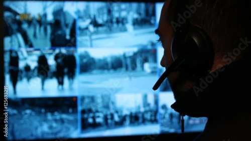 Security officer watching monitoring displays in control room. Security cameras