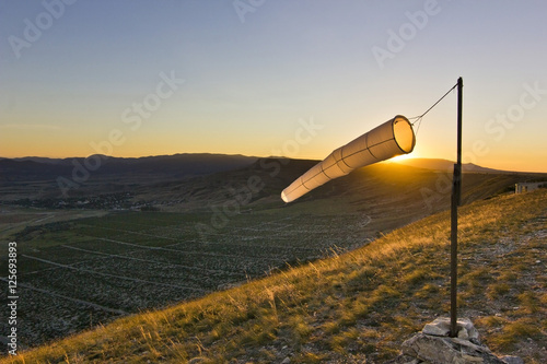 windsock at sunset in mountains against sun photo