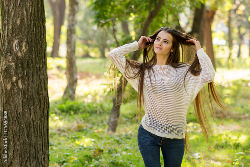 Girl with brown long hair in park by the tree