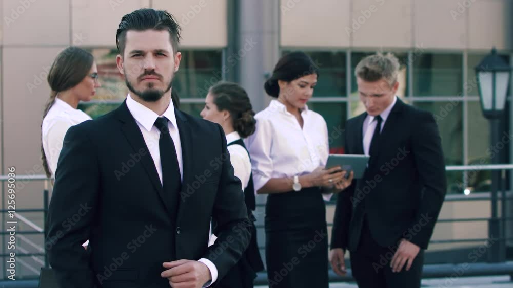 Portrait of a confident business man standing in front of his coworkers Portrait of a confident business man standing in front of his coworkers
