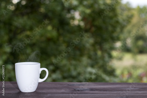 cup of coffee on green bokeh background. Image with copy space