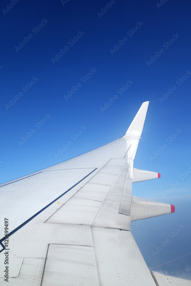 Obraz premium Wing of an airplane on blue sky