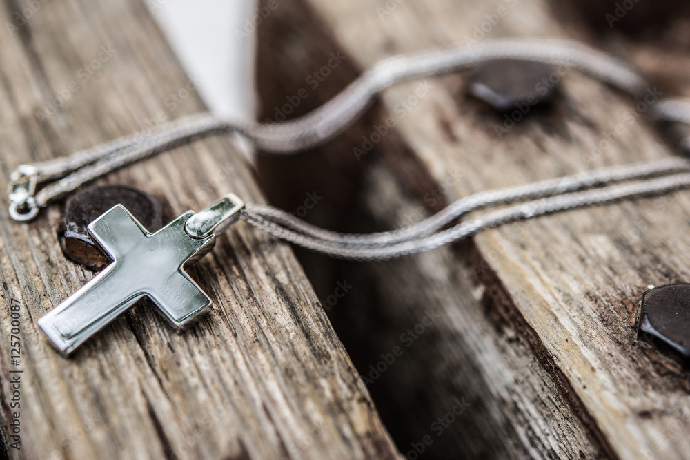 Silver christian cross on wooden bench