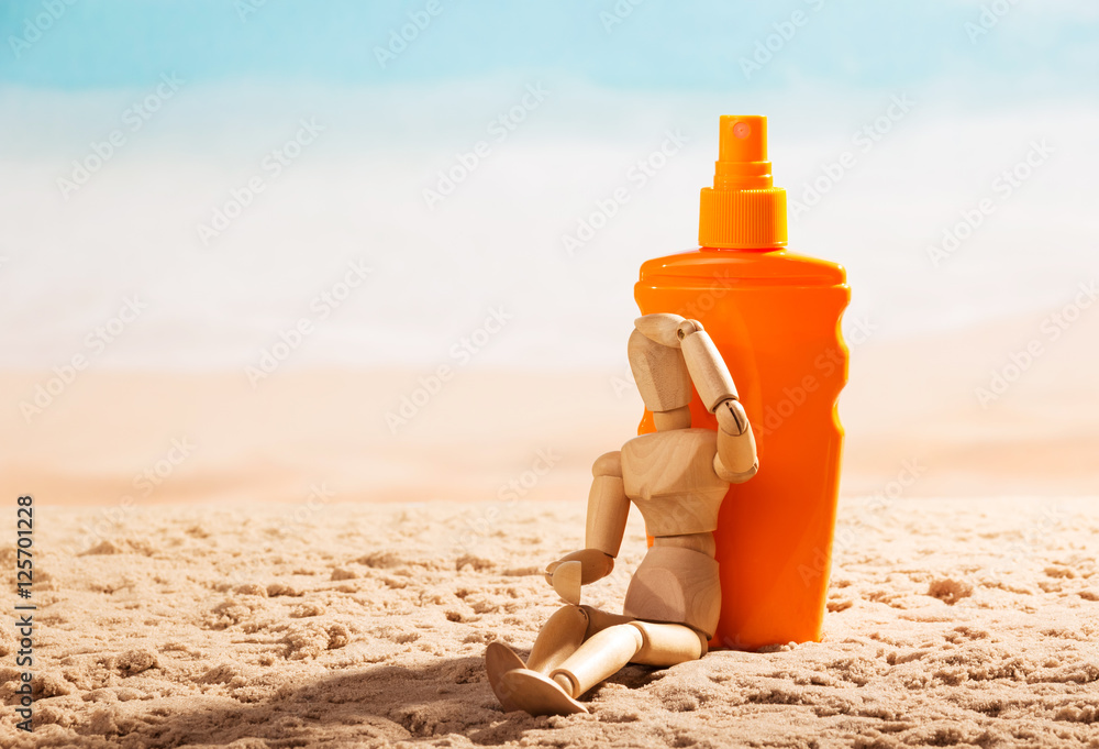 Wooden mannequin and sunscreen at beach. Wooden mannequin and sunscreen at beach.