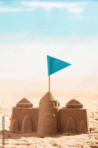 Castle in tsand and flag close-up on background sea.