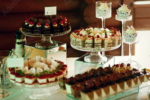 Tasty fruit and chocolate cakes stand on glass plates