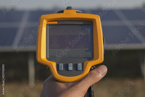 electrician working on maintenance equipment at industry solar power; engineer use IR camera to check temperature loss of solar panel 