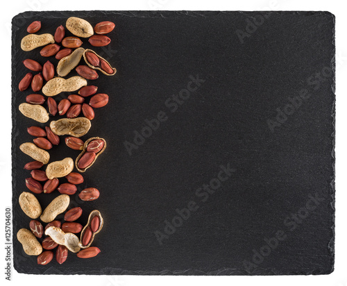 Peanuts on black slate board. Isolated on white background.