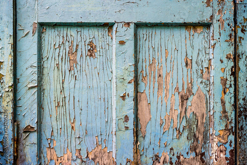 Fragment of old wooden door with peeling blue paint © ansyvan