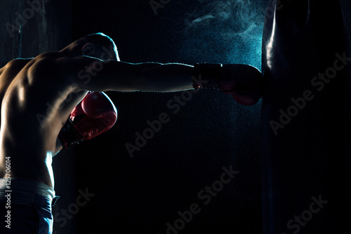 Male boxer boxing in punching bag